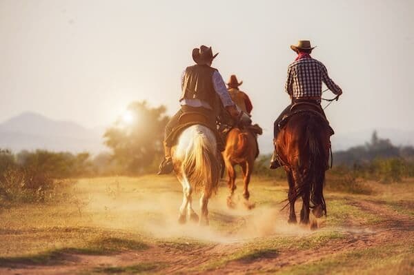 Trois cowboys au galop sur leurs chevaux